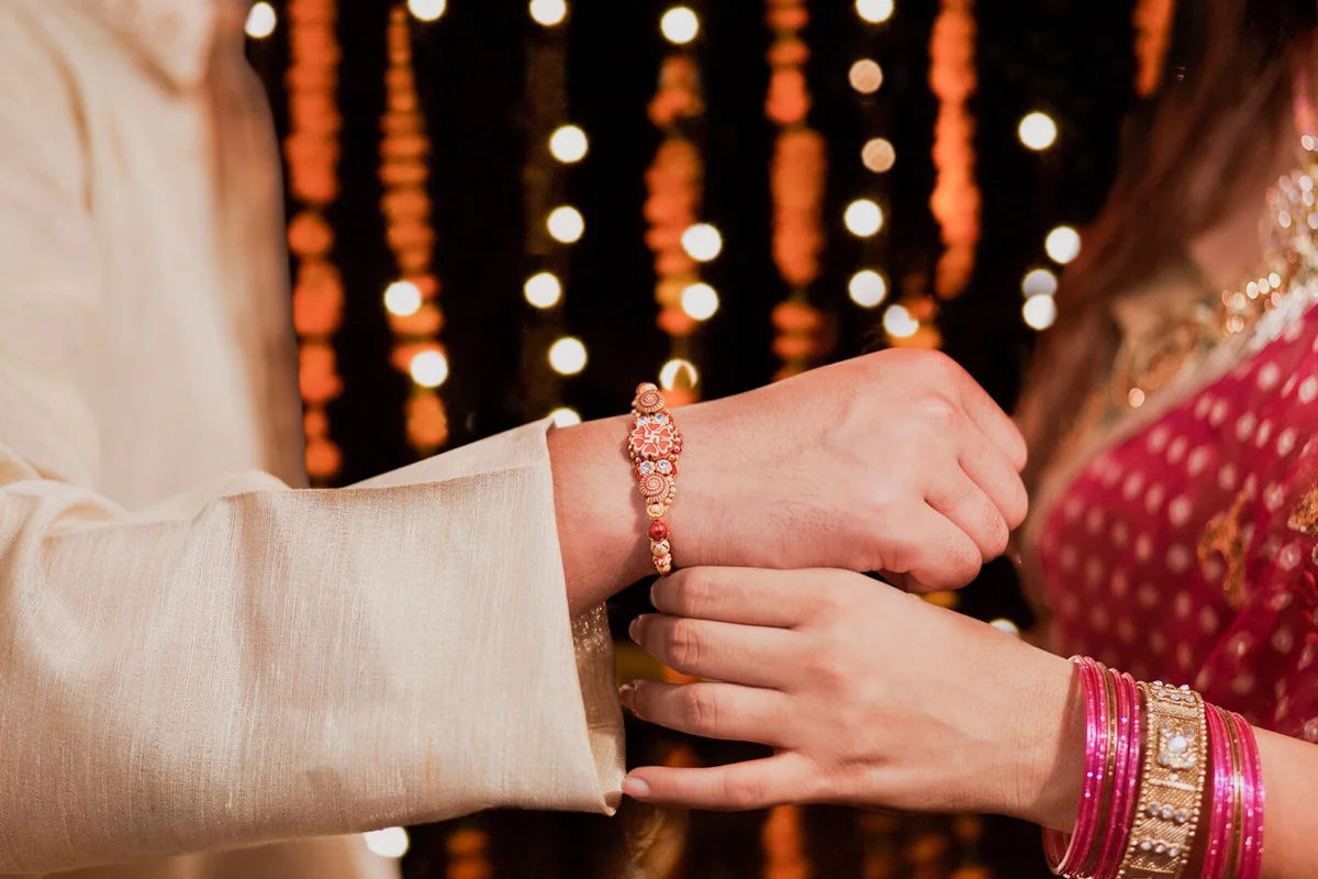 Woman tying rakhi on her brothers hand