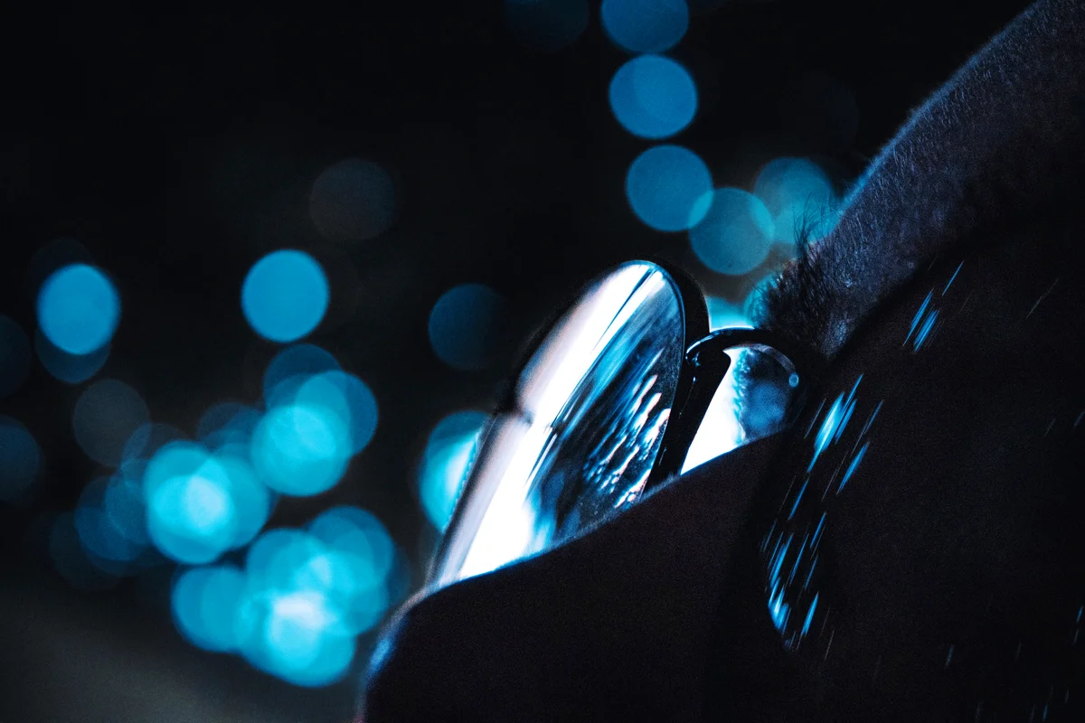 Woman Wearing Eyeglasses Against Blue Lens Flare At Night