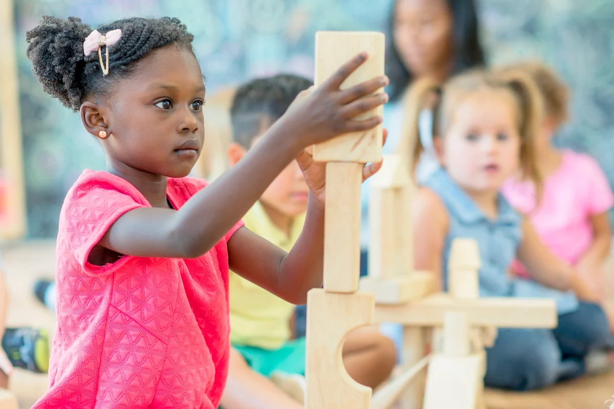 Girl Stacks Blocks at Preschool