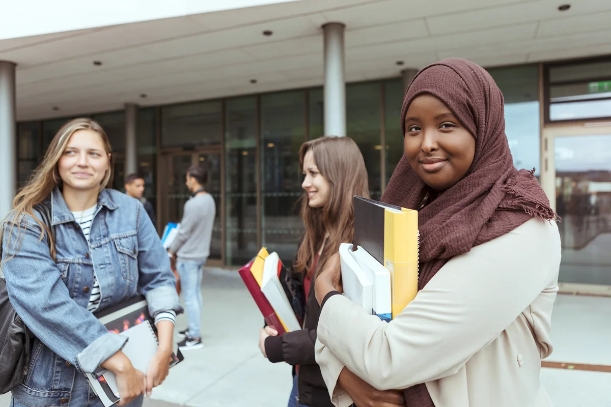 Student in hijab standing with friends at university campus