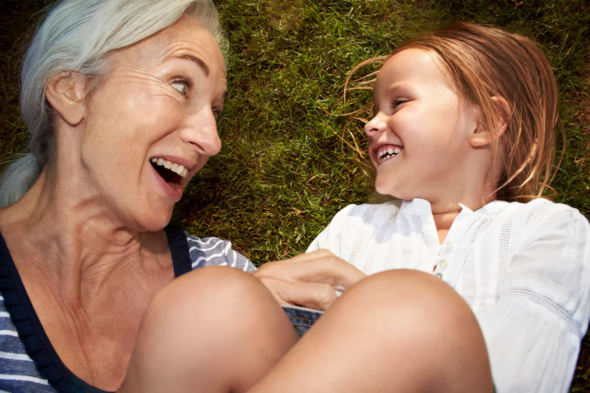 Grandmother and granddaughter lying in grass