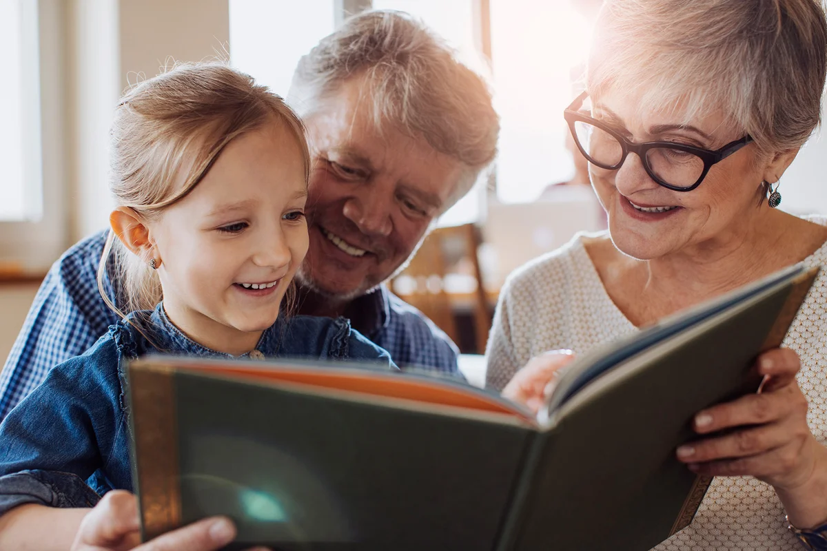 Grandparents reading a book to their granddaughter