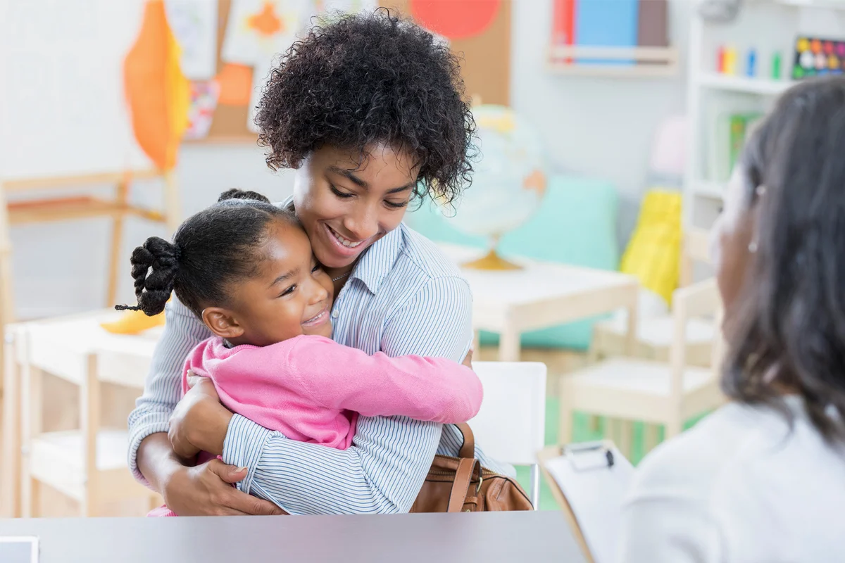 Little girl hugs mother during day care interview