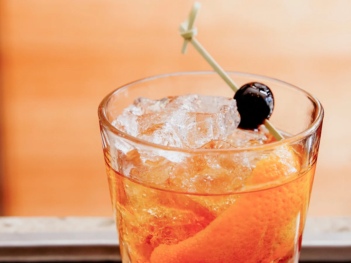 whiskey cocktail with maraschino cherry, bitters and orange peel