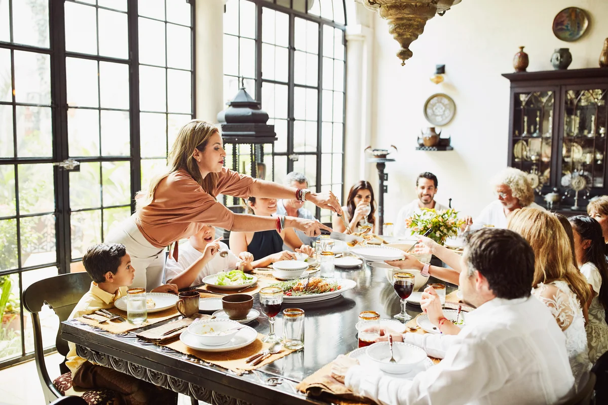 Woman serving family members at dining room table during celebration meal