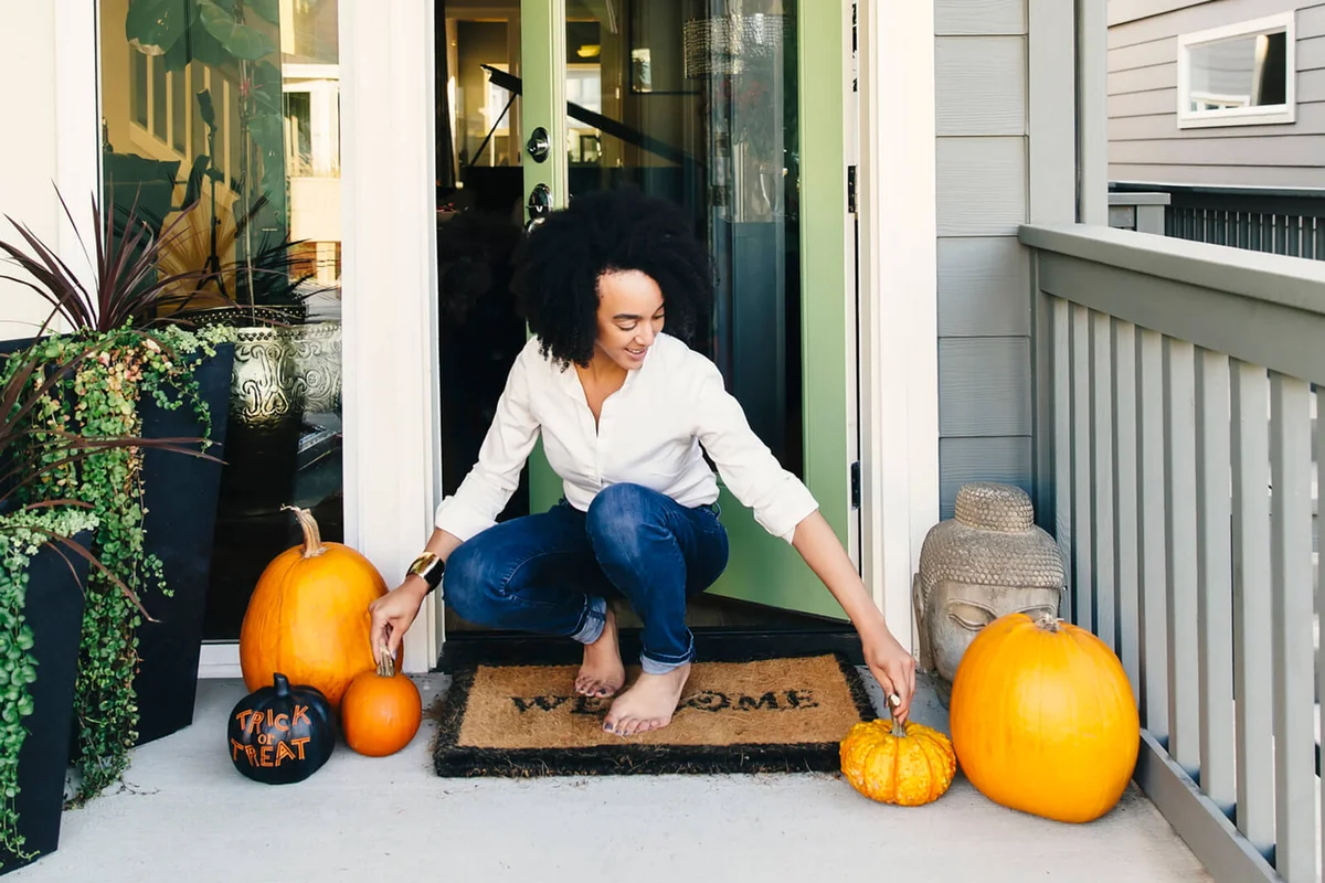 woman arranging pumpkins on patio