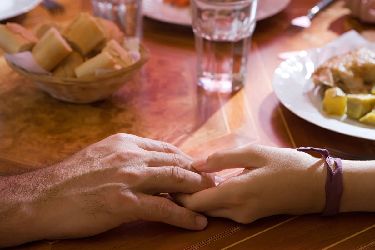 Holding hands at dinner table