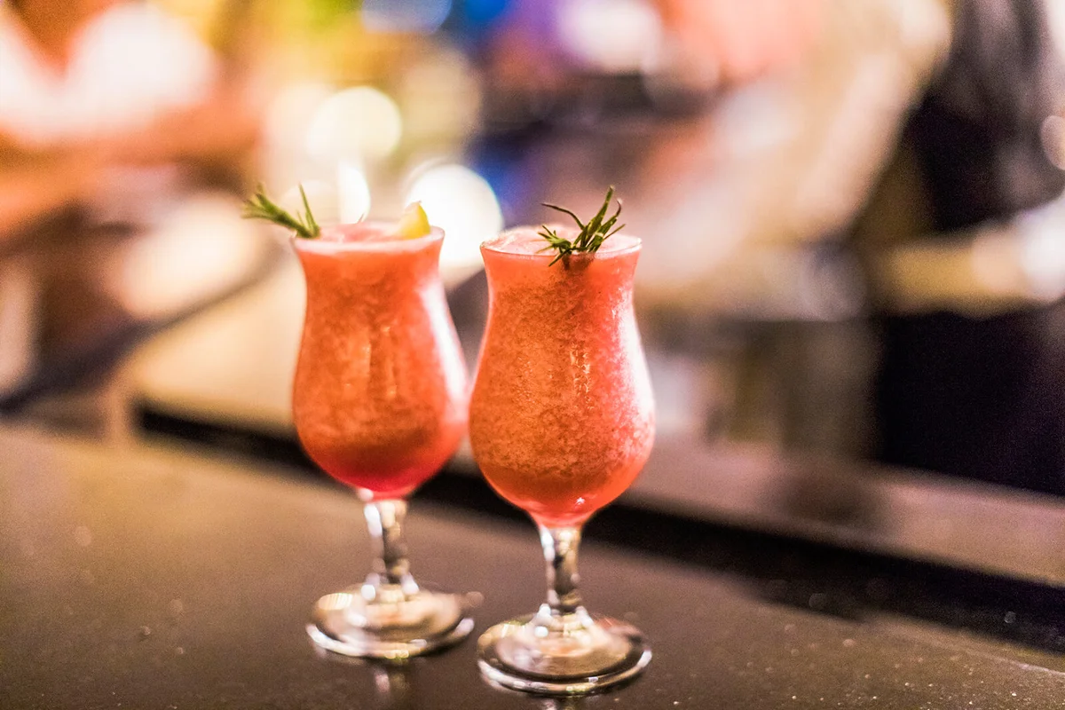 Two fresh strawberry daiquiris, decorated with a sprig of thyme and a slice of lime