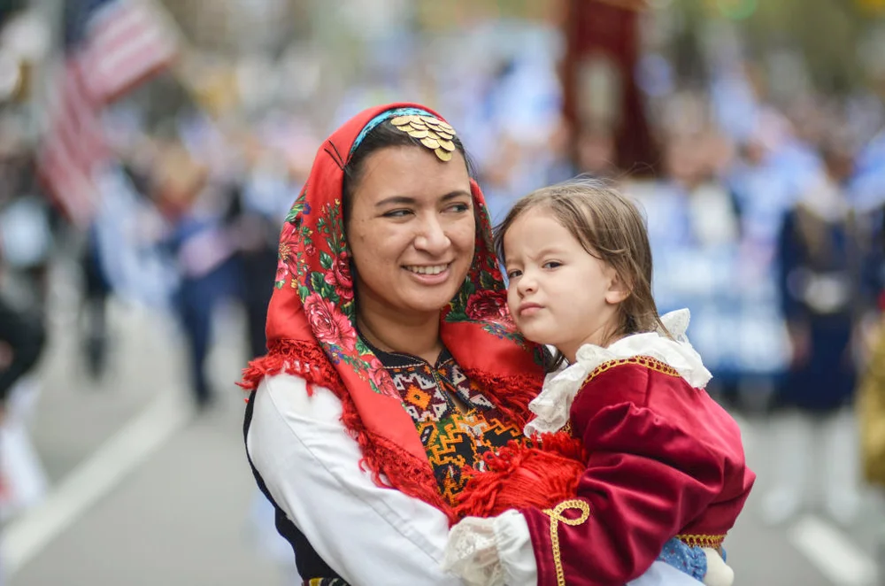 A mother seen marching with her young child during the Greek Independence Day parade in Manhattan