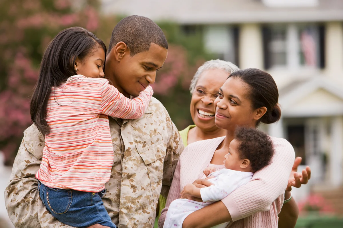 African American military father hugging family