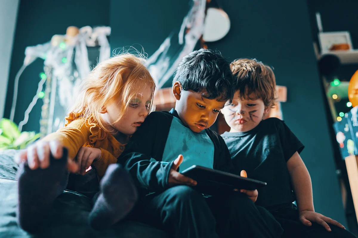 Three children sitting on a beanbag looking at a computer tablet