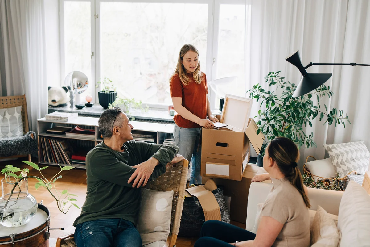 Young woman talking with parents while unpacking