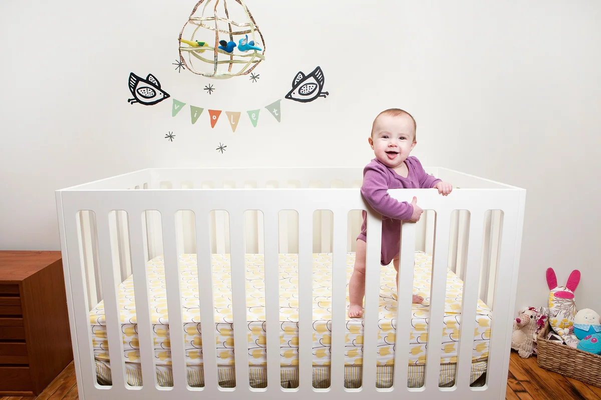 Baby in crib surrounded by toys