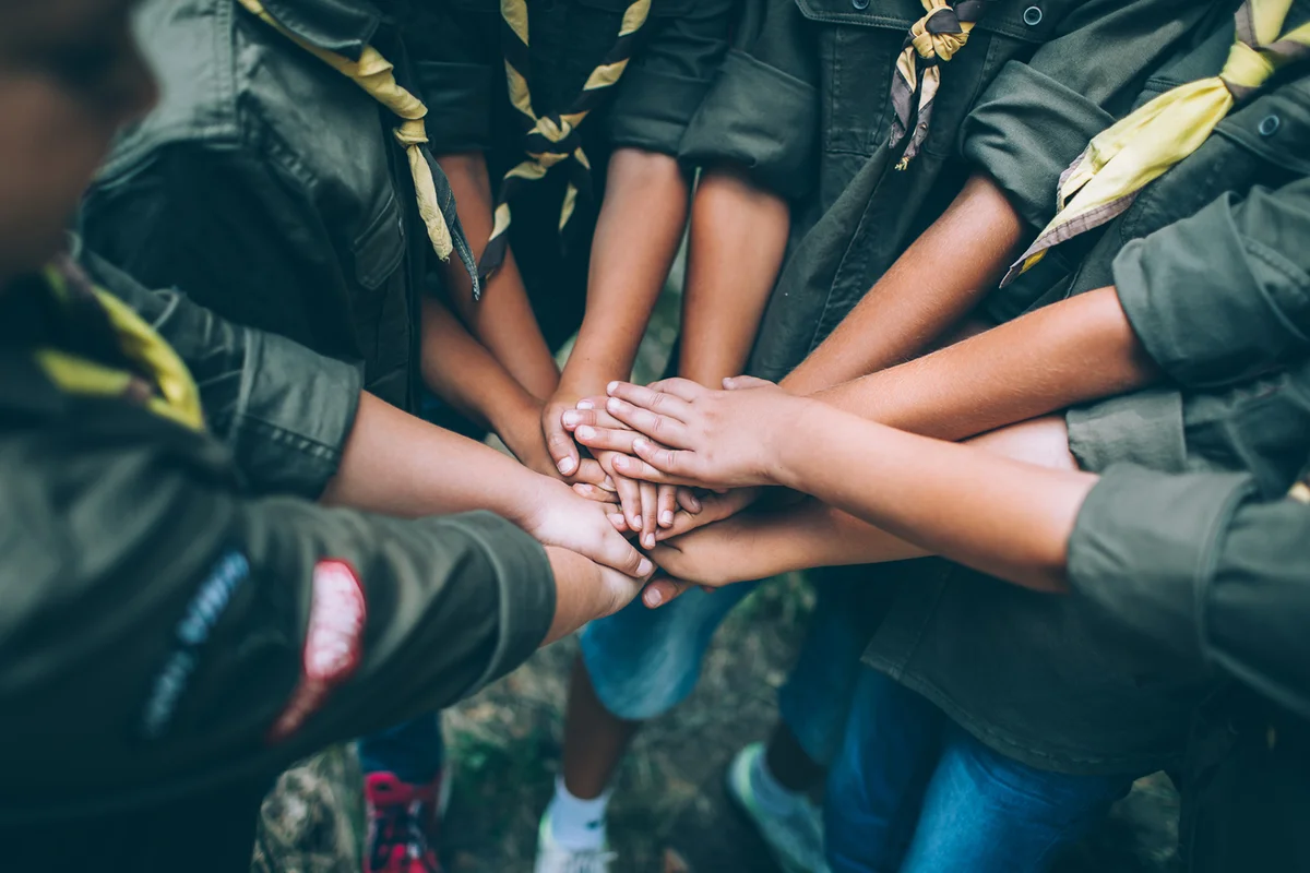 Group of young scouts joining hands together