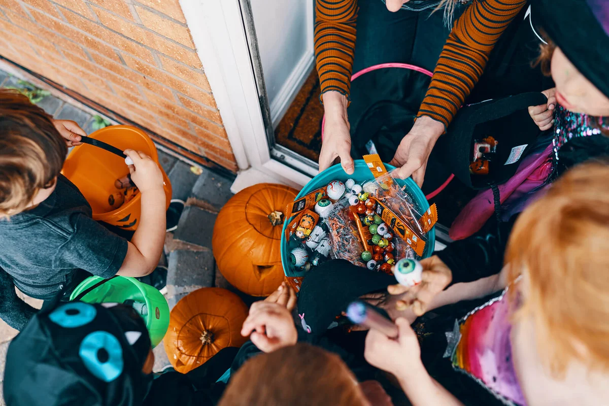 group of children at a front door taking sweets from a bowl at Halloween
