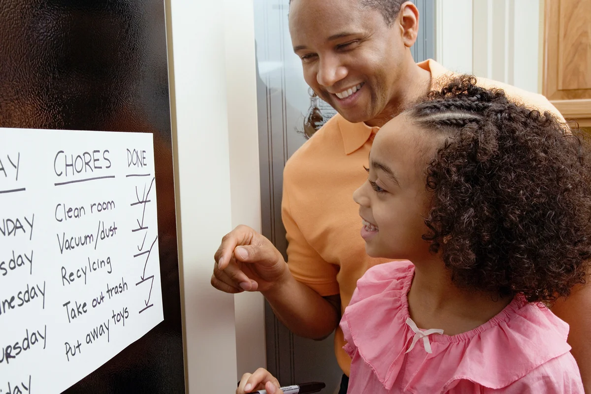 African father and daughter looking at chores chart