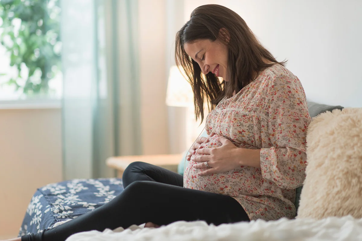 Pregnant woman sitting on bed