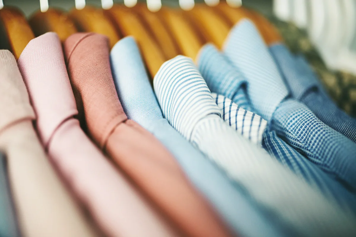 Assortment of mens shirts on wooden coat hangers