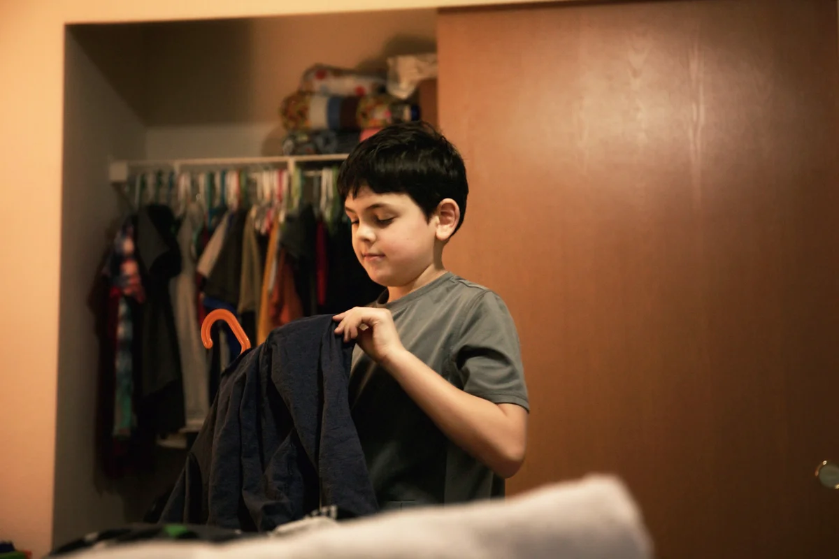 Young boy putting his clothes away