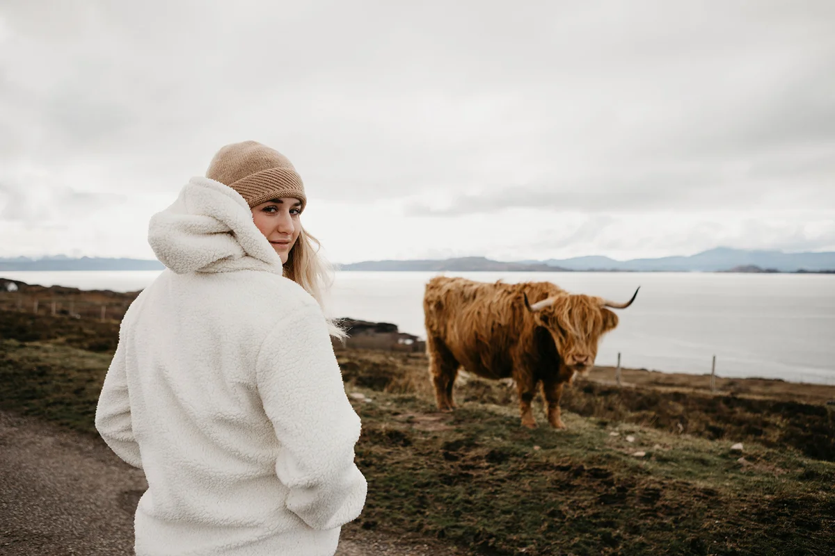 Young woman and longhorn cattle on pasture Scotland