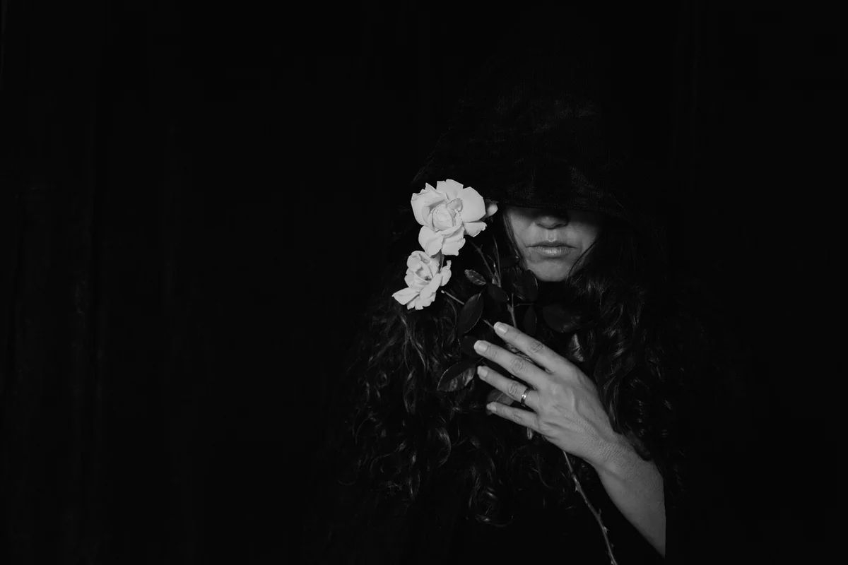 Young Woman Holding Flower Over Black Background
