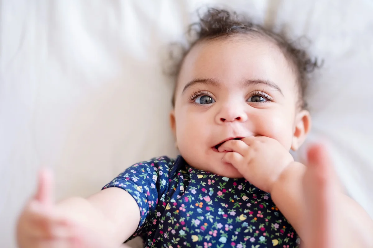 Cute baby girl lying on bed and playing with her toes