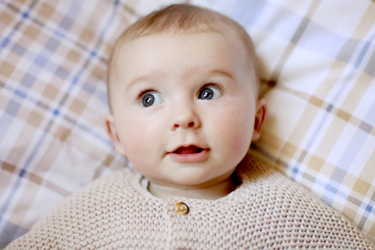 A 5 month old baby girl laying on a bed