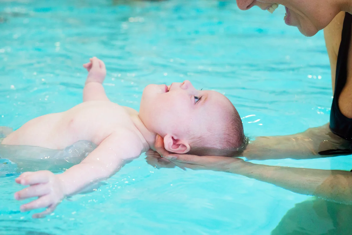 Mother teaching infant how to float in swimming pool