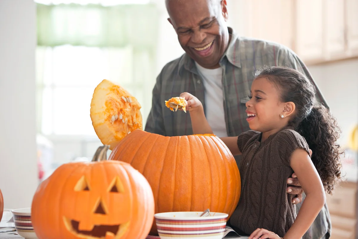 Grandfather and granddaughter carving a pumpkin