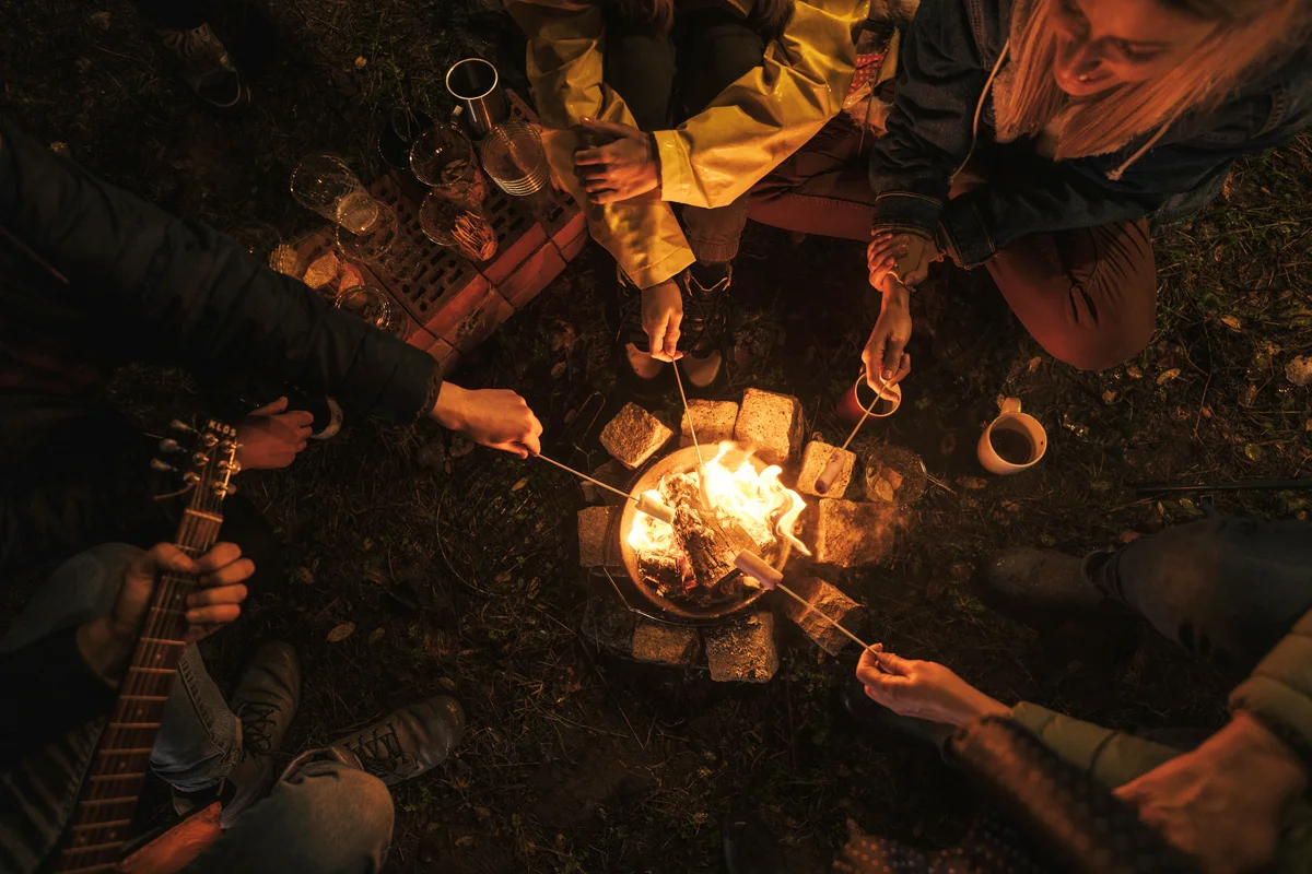 Friends roasting marshmallows and playing guitar by the campfire