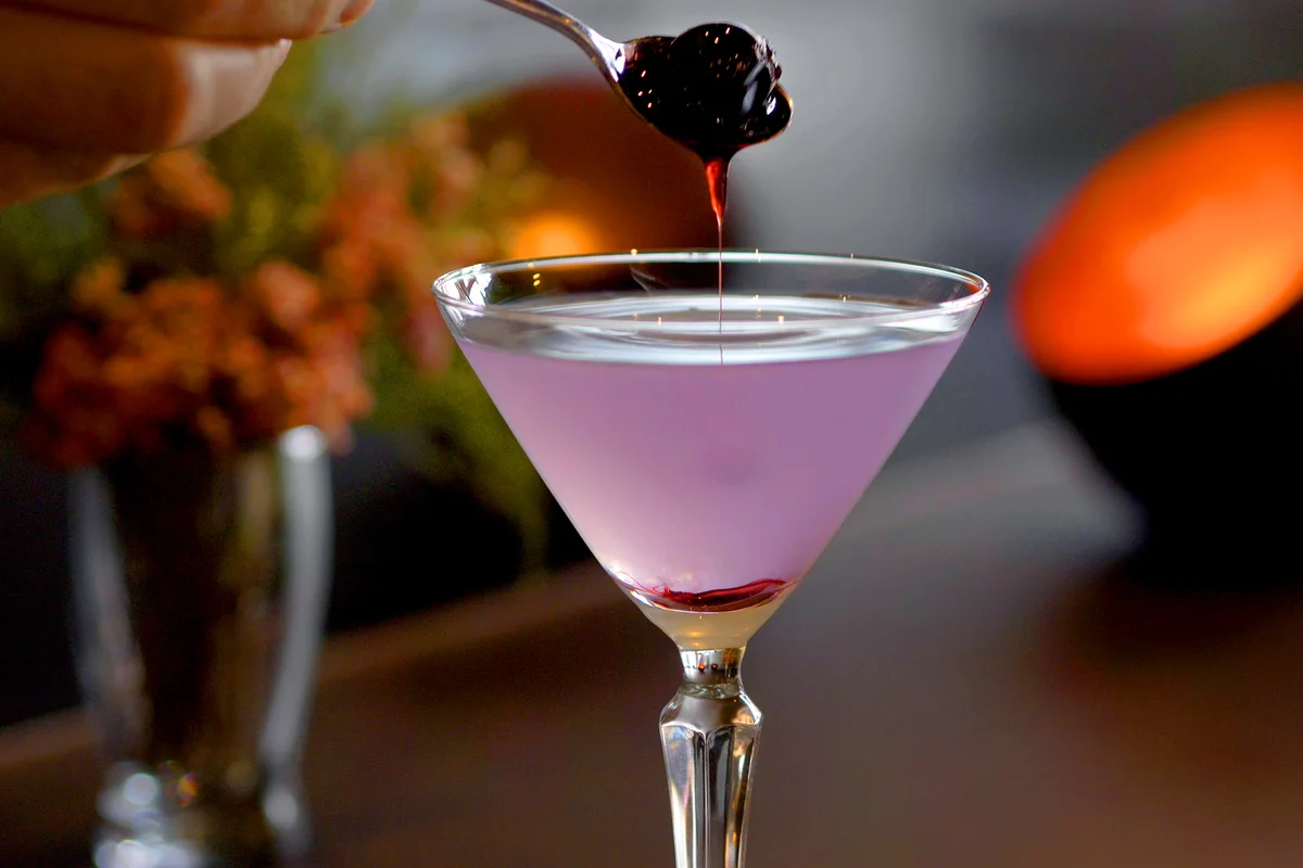 Cocktail with gin, crème de violette and cherry poured into martini glass