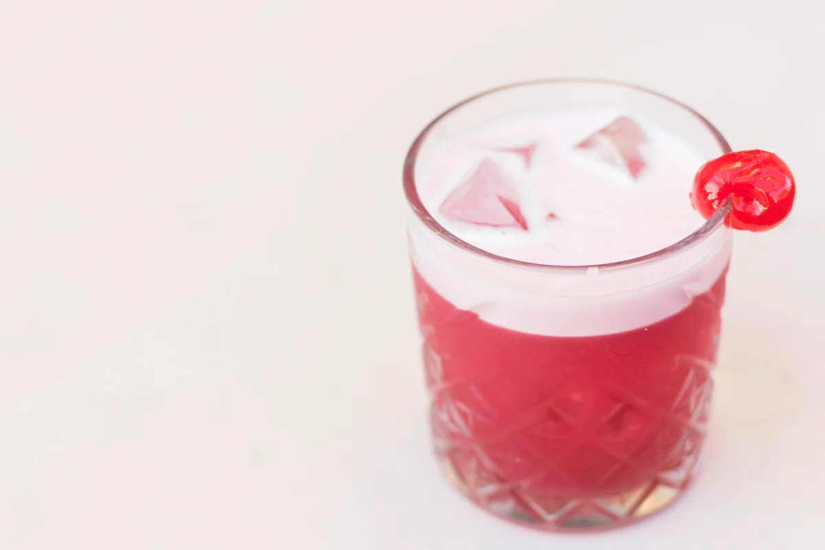 Pink cocktail with cherry, in an old fashioned glass
