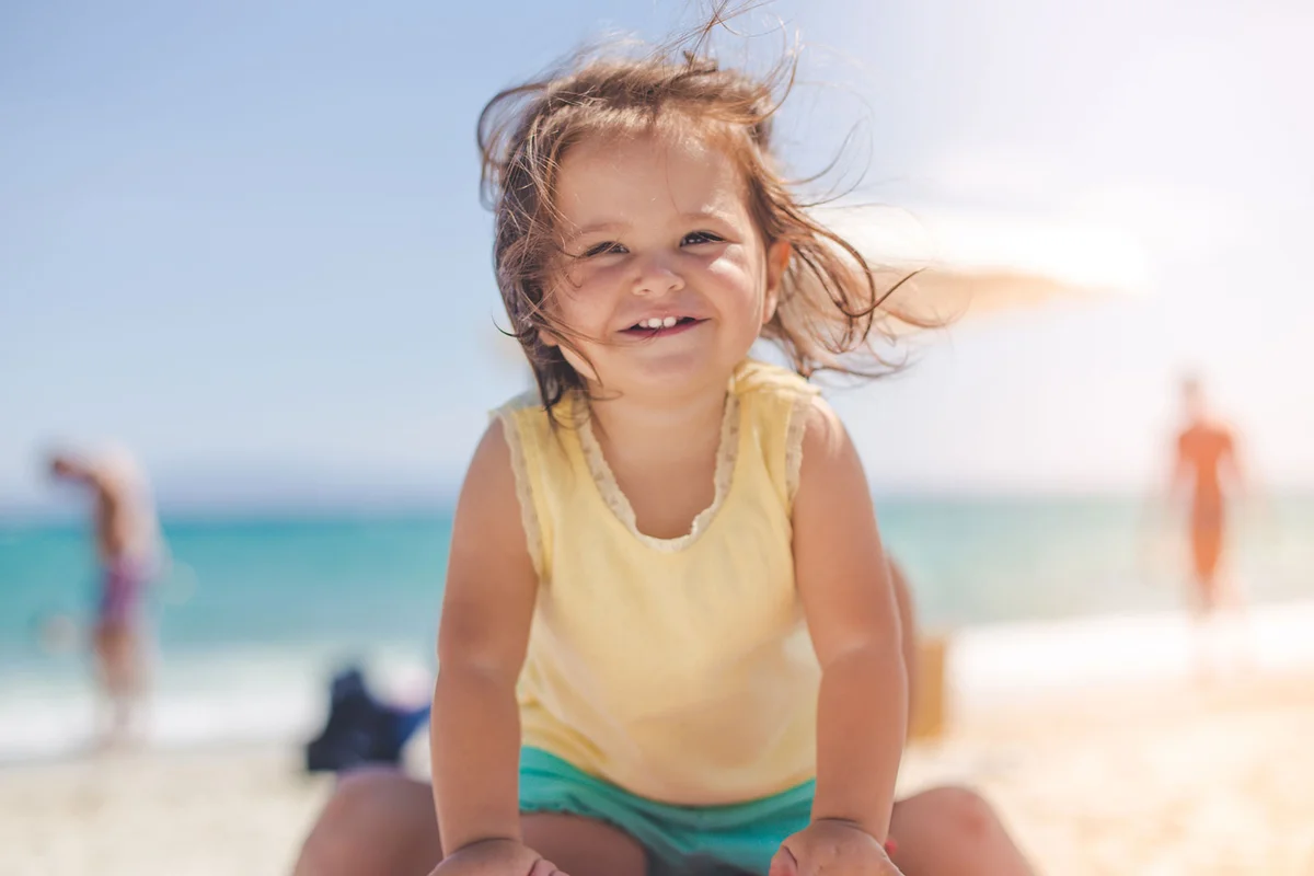 toddler girl smiling at the beach