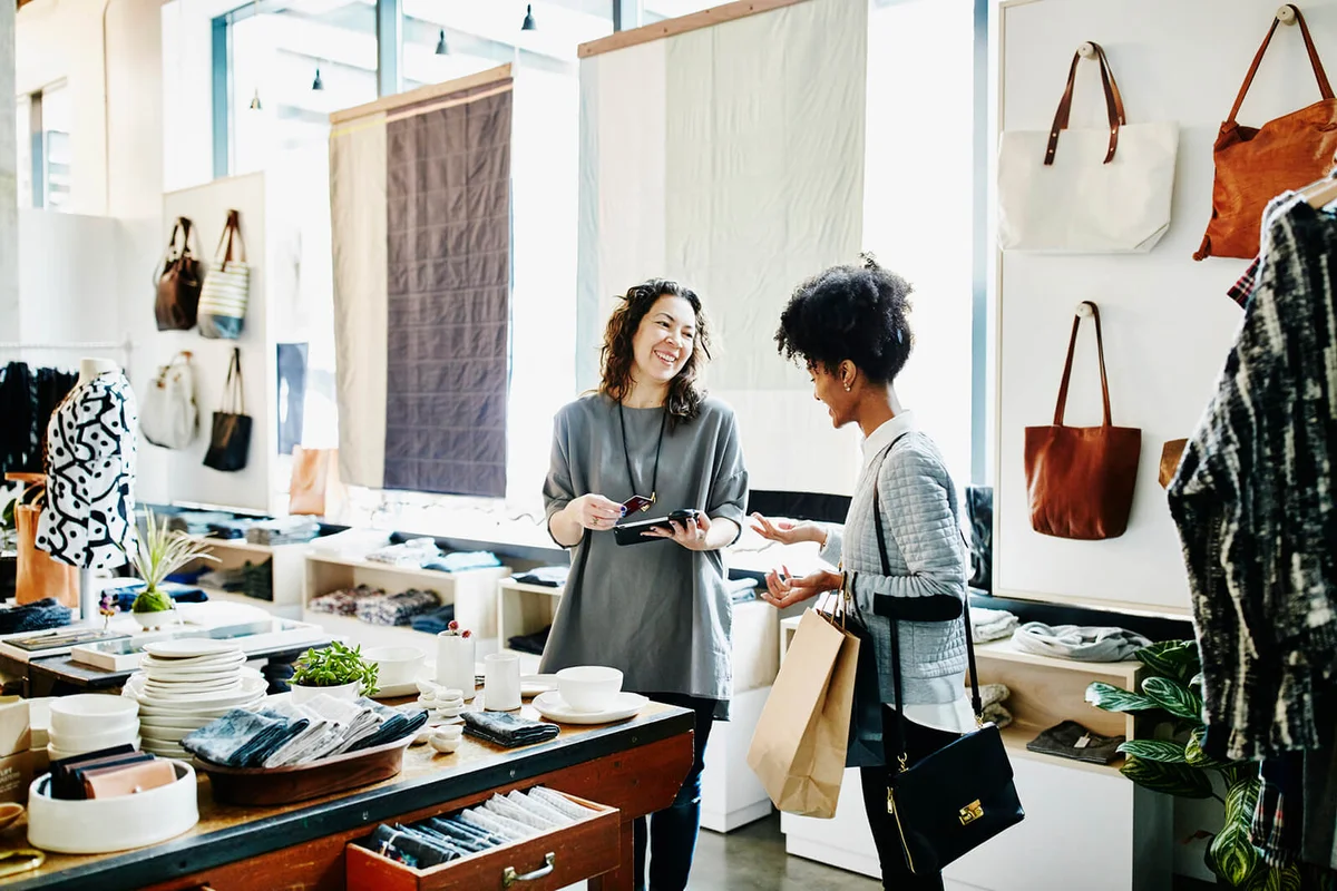 business owner completing transaction for customer on digital tablet in boutique shop