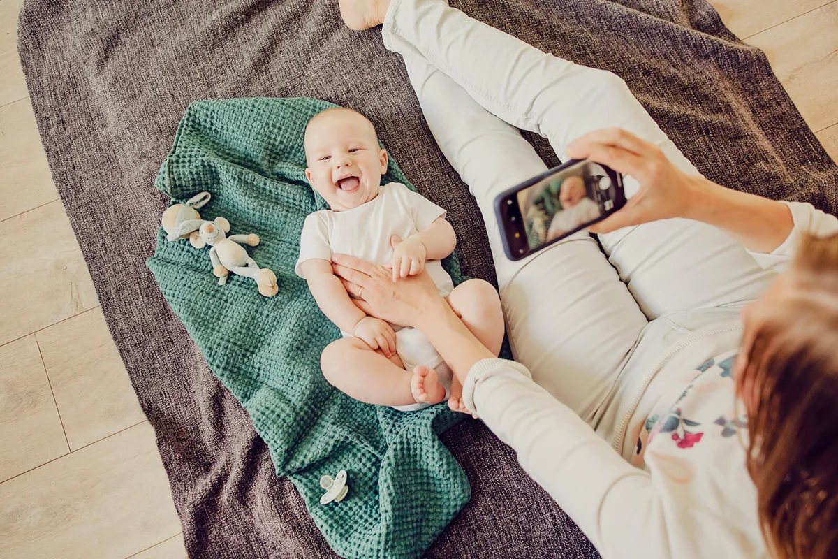 Mother photographing her baby using mobile phone