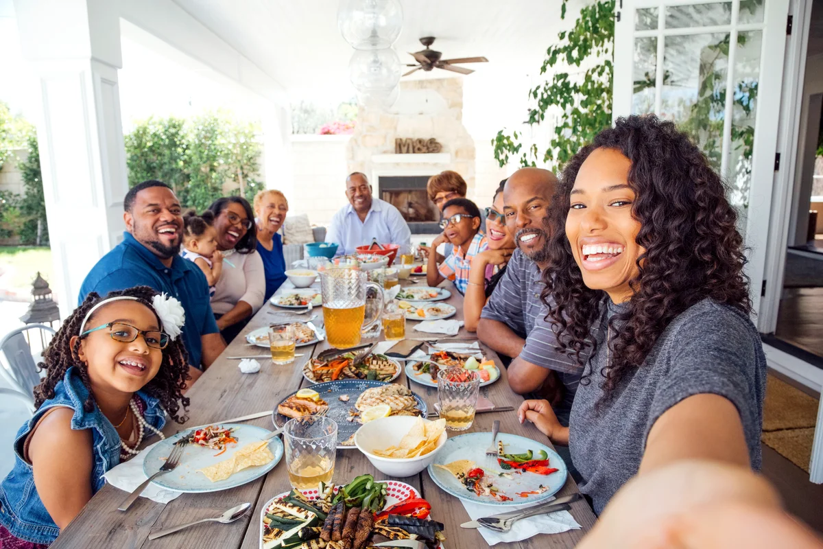 Smiling woman taking selfie with family at lunch party