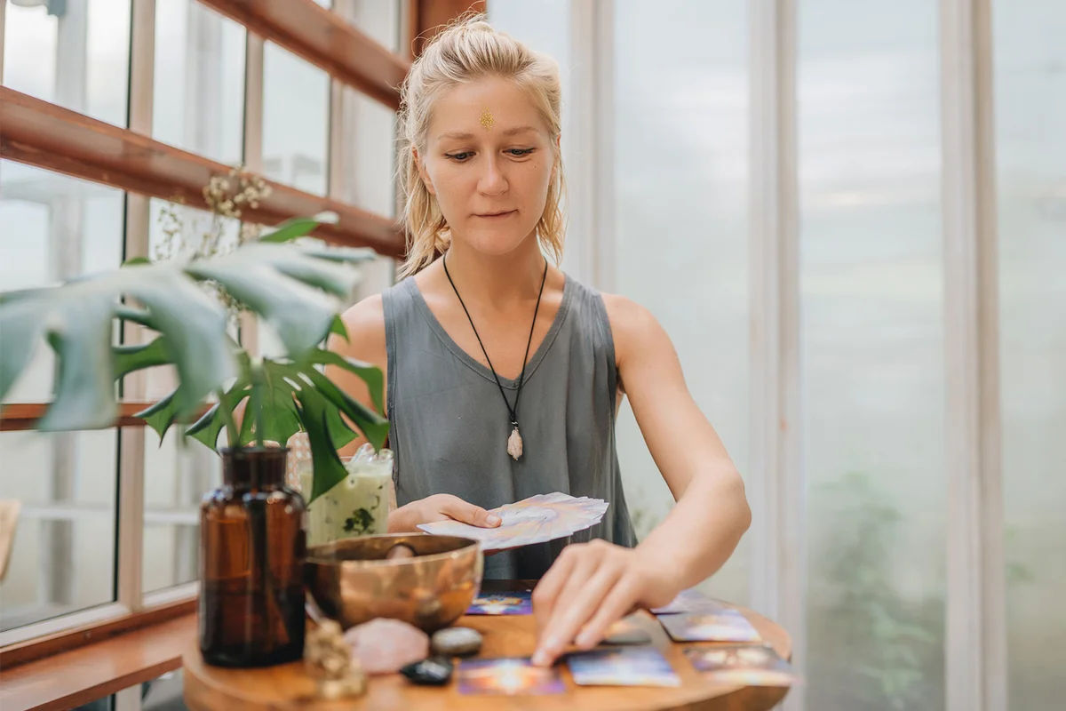 Woman is reading Tarot cards on a table in cafe