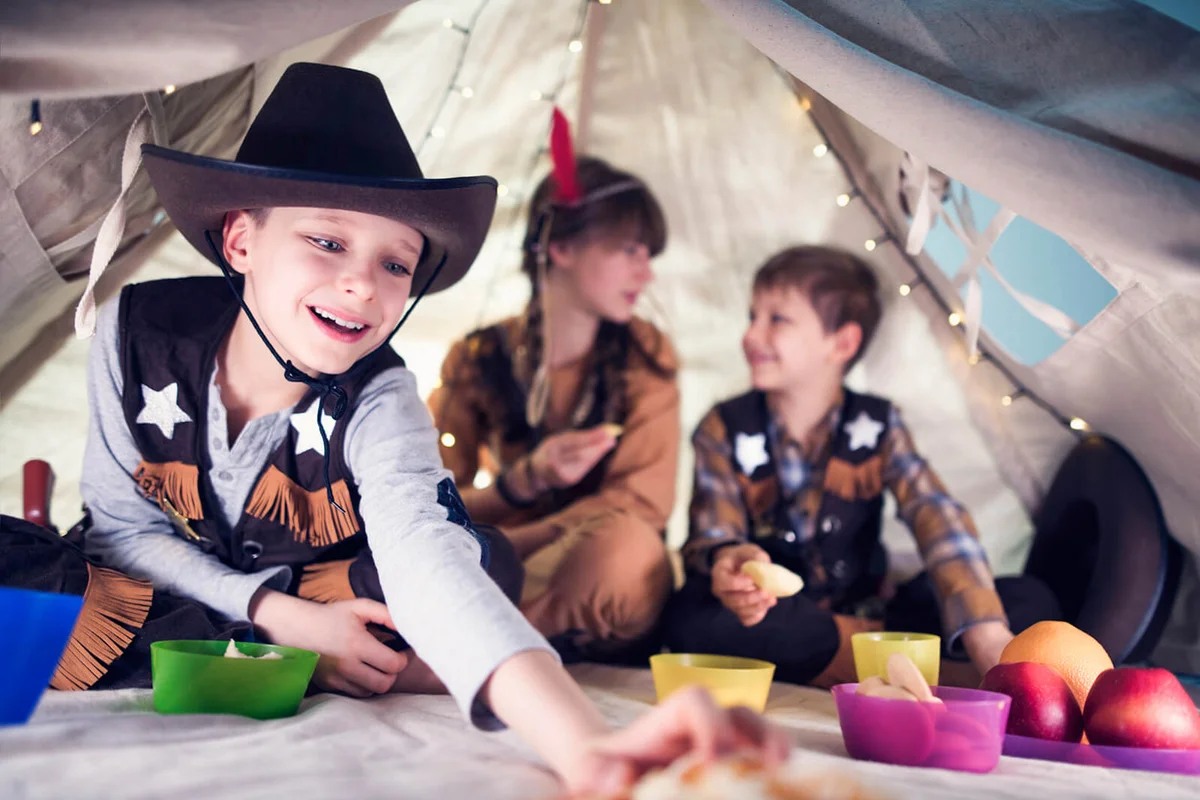 Kids dressed up as cowboys and squaw are having fruit and snacks