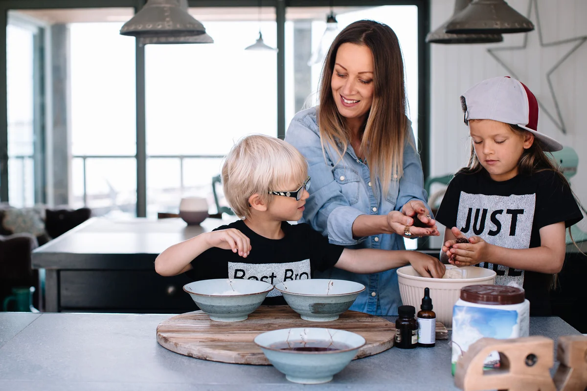 Children baking in the kitchen handling food with mother