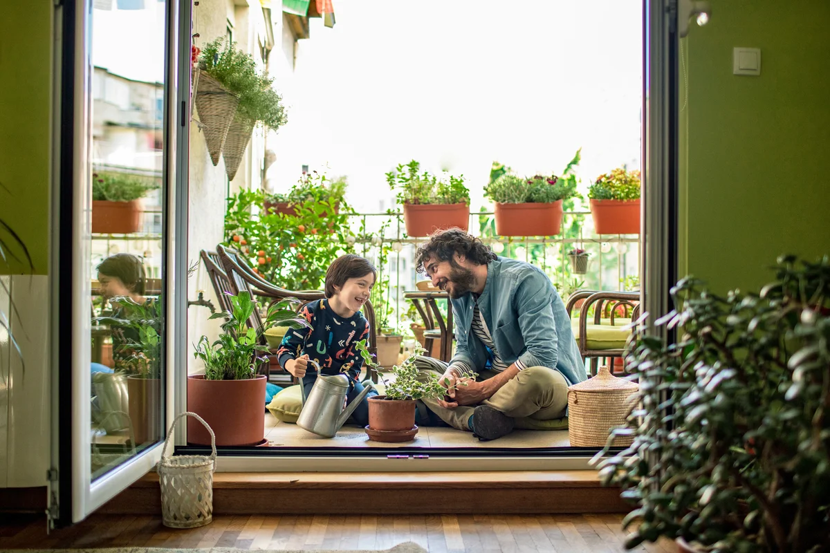 Father and son watering plants on their terrace