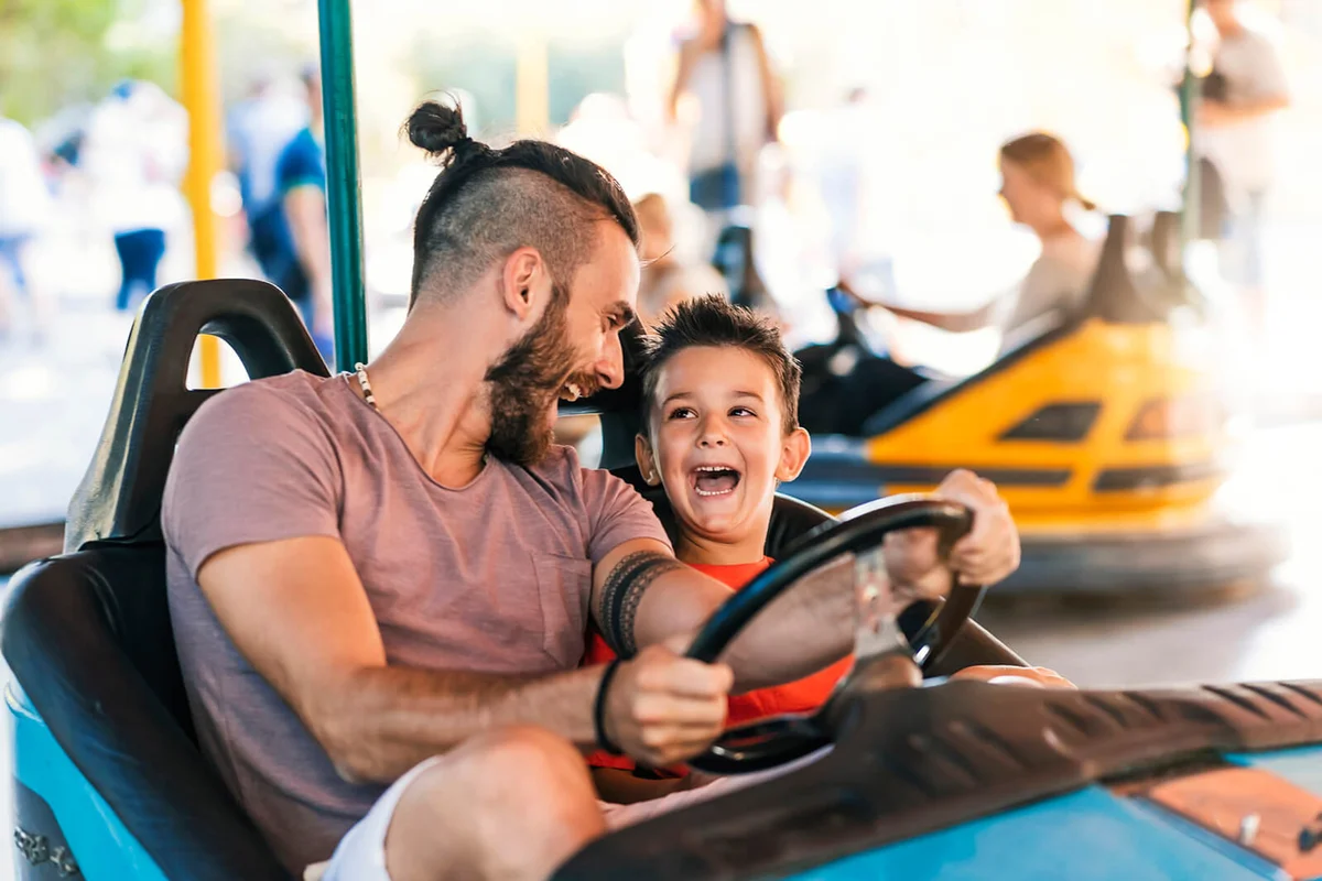 Father and his 5 years old son having a ride in the bumper car at the amusement park