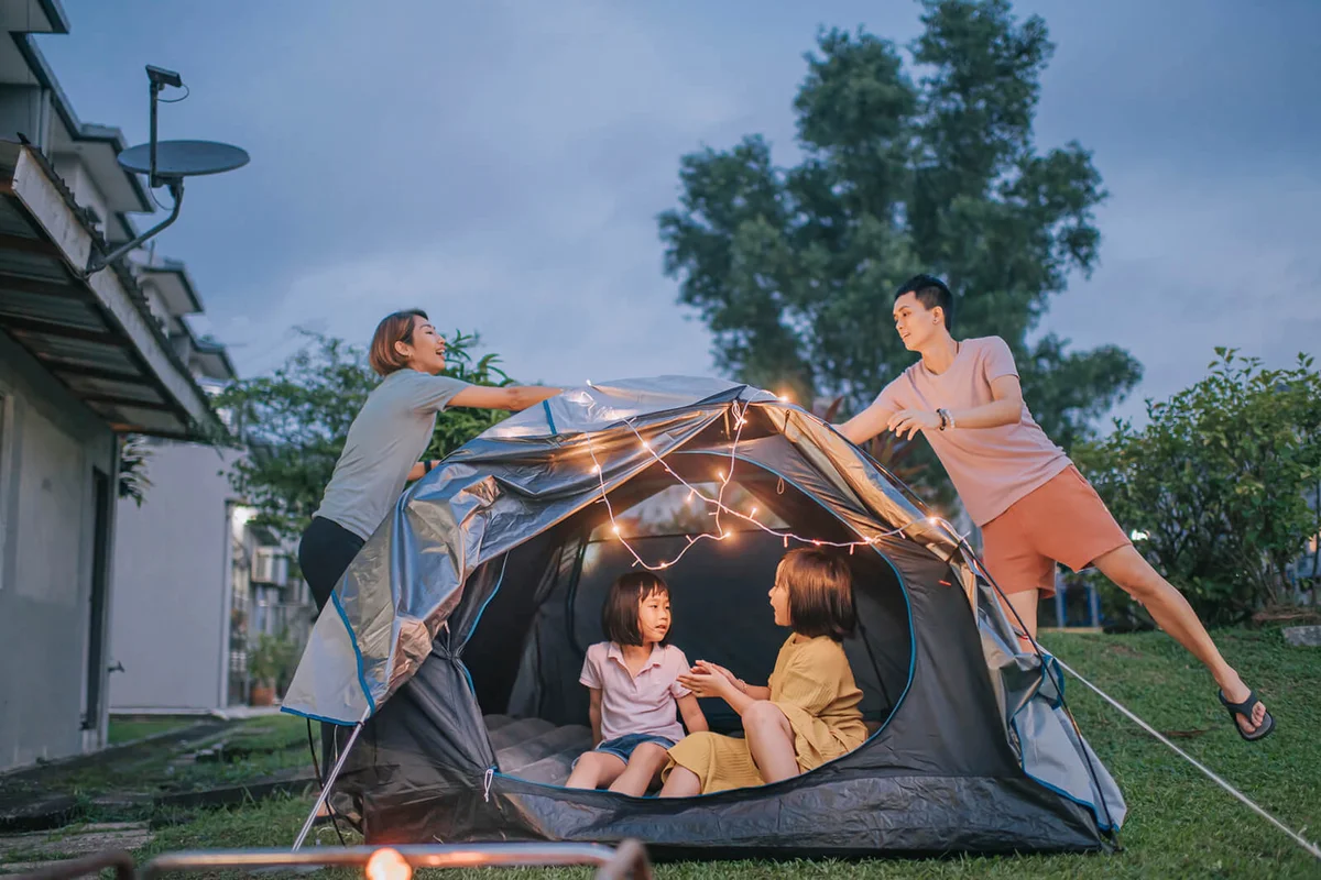 family putting on string light decorating camping at backyard of their house