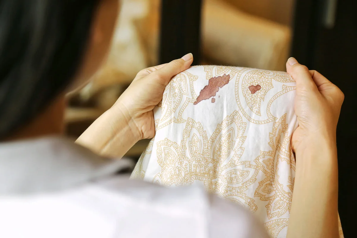Women hold bed sheet with period blood spot stains on blur background