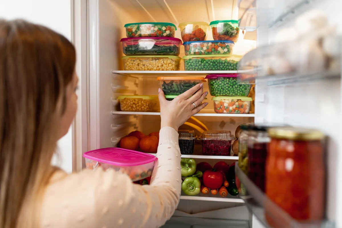Woman taking leftovers from refrigerator