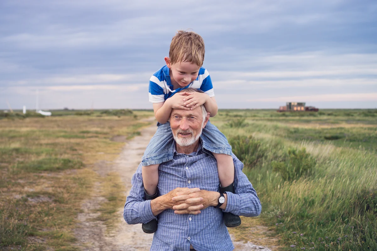 Young boy being carried by his grandad