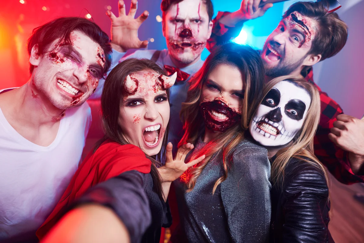 Friends in creepy costumes having fun at Halloween party