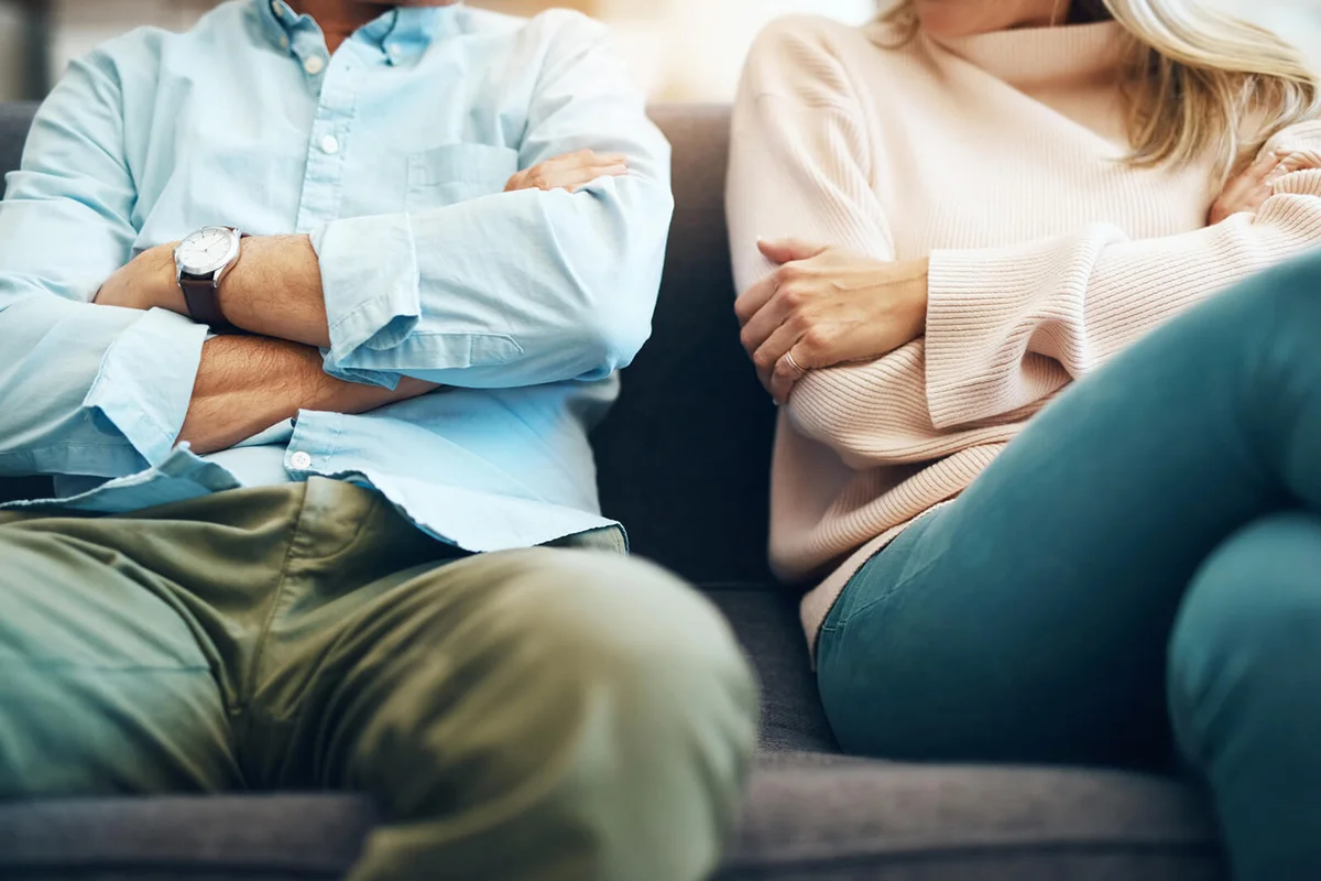 unrecognizable mature couple sitting on the sofa with their arms folded after an argument