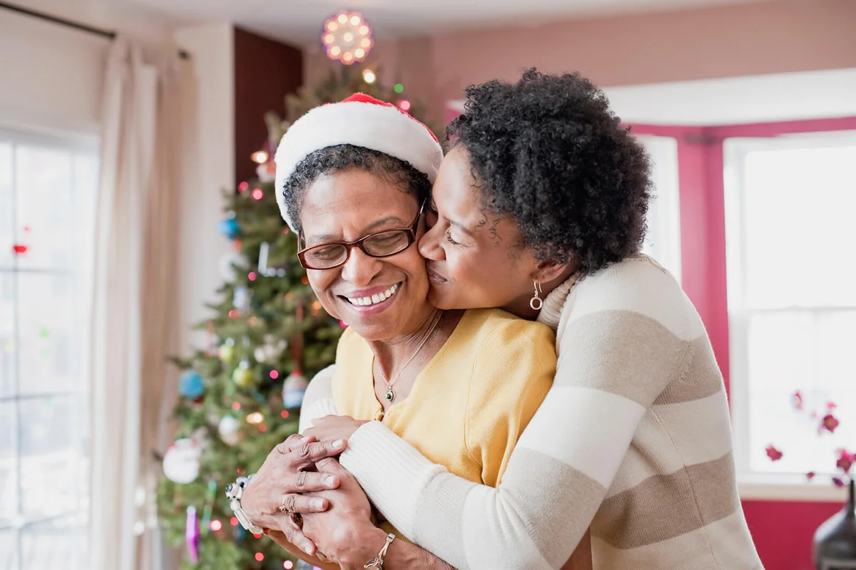 Mom and adult daughter hugging at Christmas tree