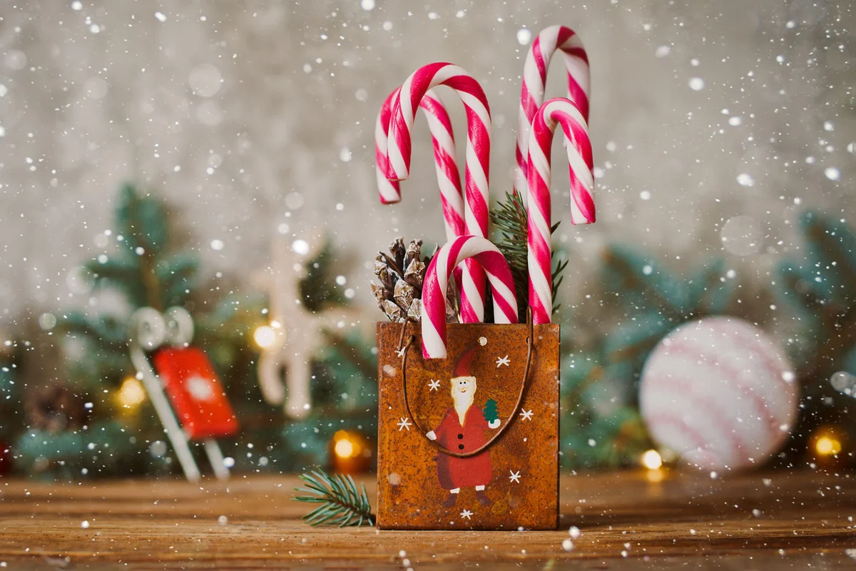 candy canes displayed in a vintage Christmas tin container