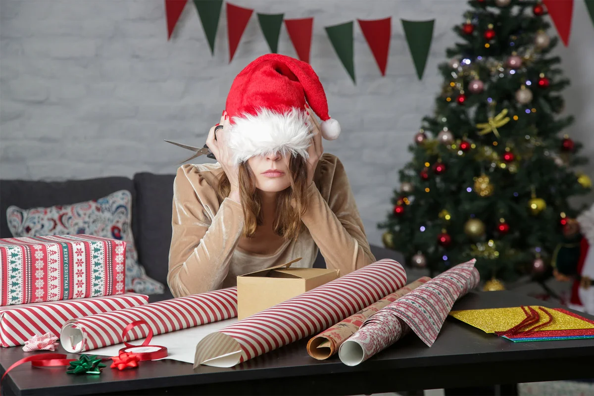 frustrated woman wrapping presents on Christmas Eve